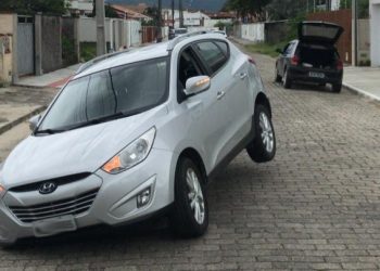 Cratera se forma em rua e automóvel fica com roda presa